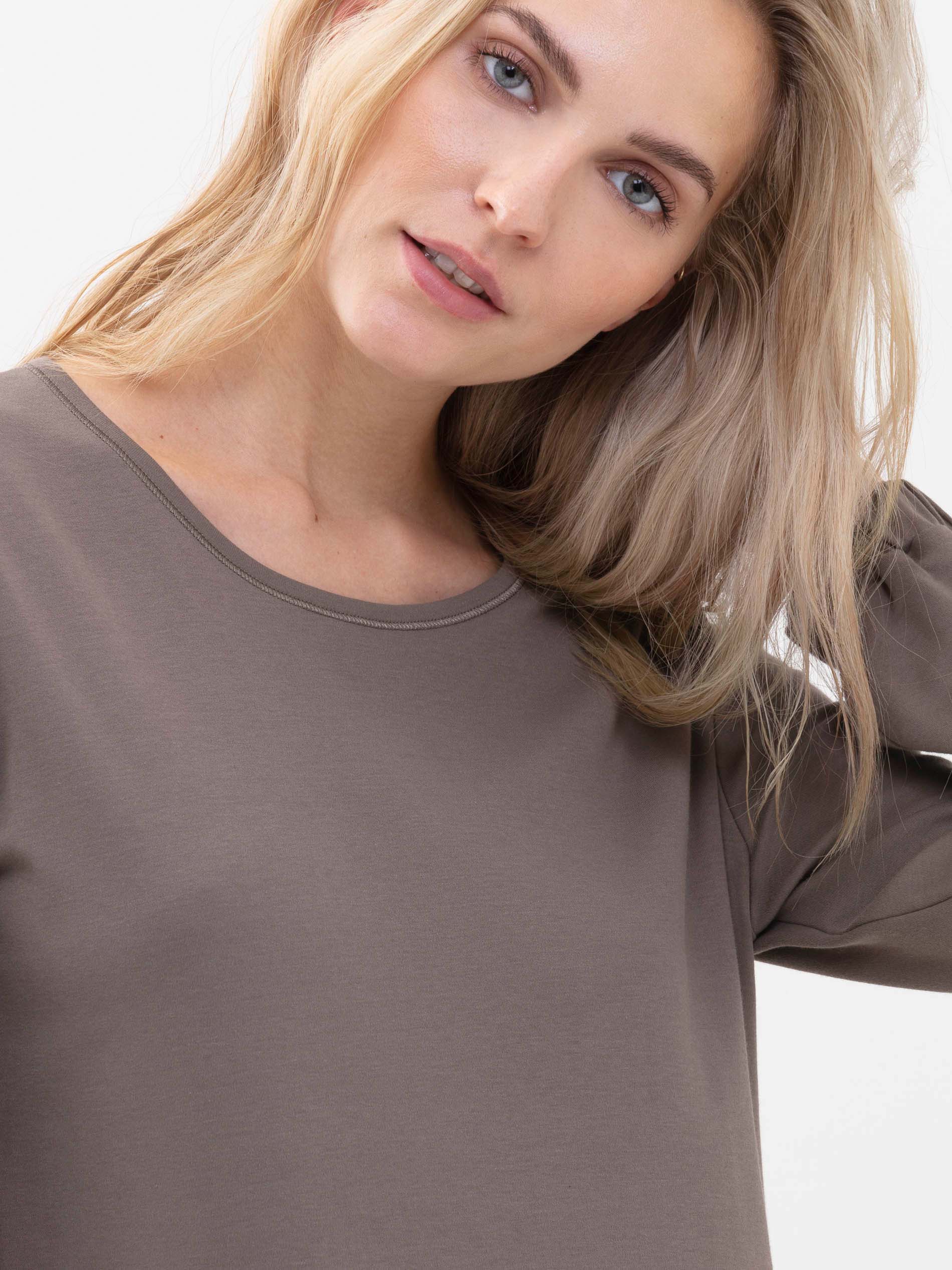Vooraanzicht van een blond damesmodel, ze draagt een T-shirt met lange mouwen uit de serie Zzzleepwear in de kleur deep taupe | mey®