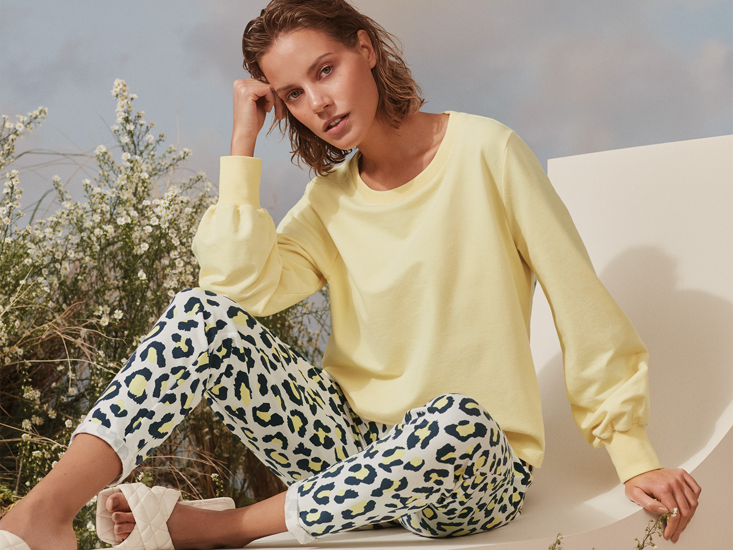 Damesmodel zit in een pastelgeel sweatshirt en een gekleurde luipaardbroek | mey® 